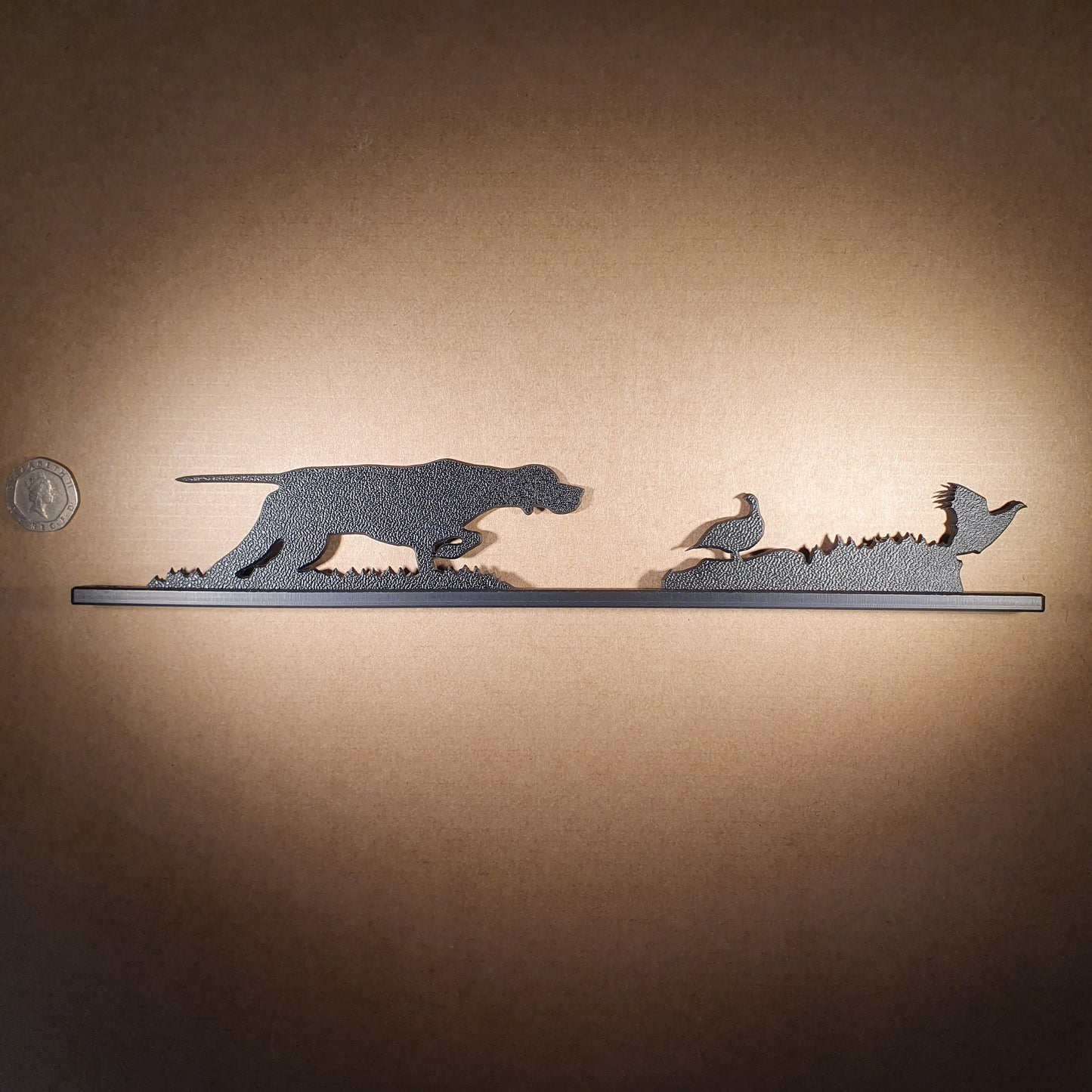 An English Pointer flushing grouse ornament made from recycled plastic pictured to display the products scale